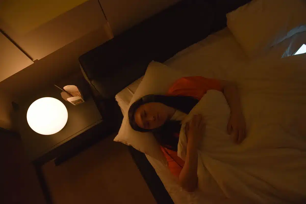 A person wearing headphones in a quiet, dimly lit space, lost in contemplation and music.
