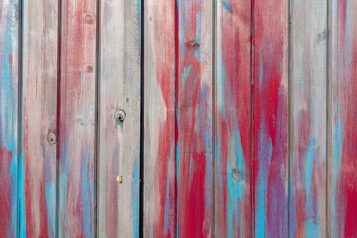 Anonym person painting a bright-colored fence or patio panel in bright daylight