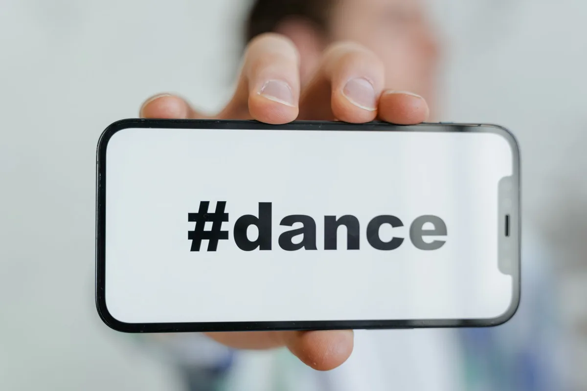 Hands holding a smartphone displaying a viral dance video with colorful background