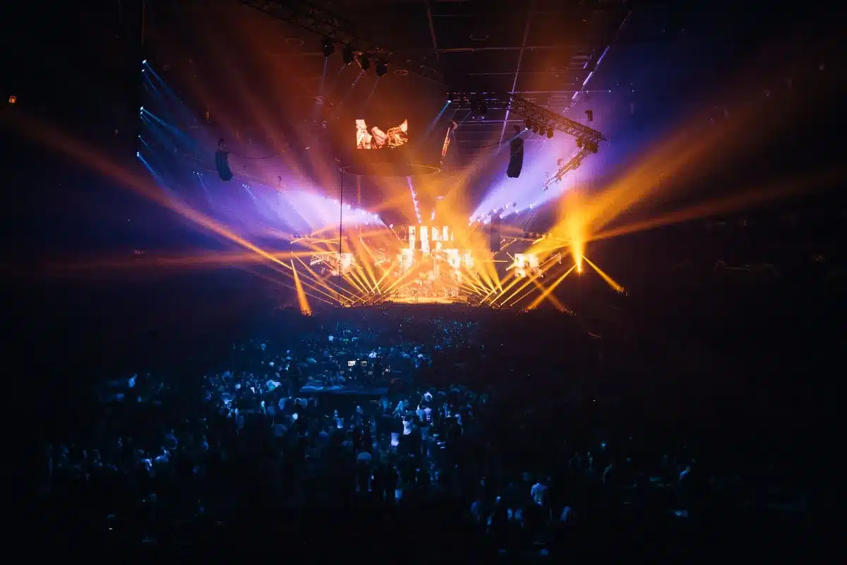 Large concert arena filled with audience members under stage lighting