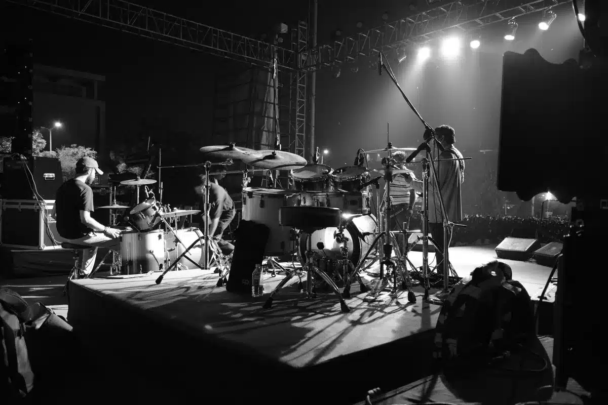 Silhouetted rock band performing on stage with guitars and drums under concert lighting