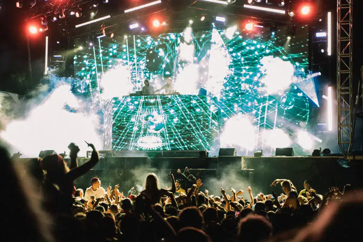 Crowd dancing at electronic music festival with colorful stage lights