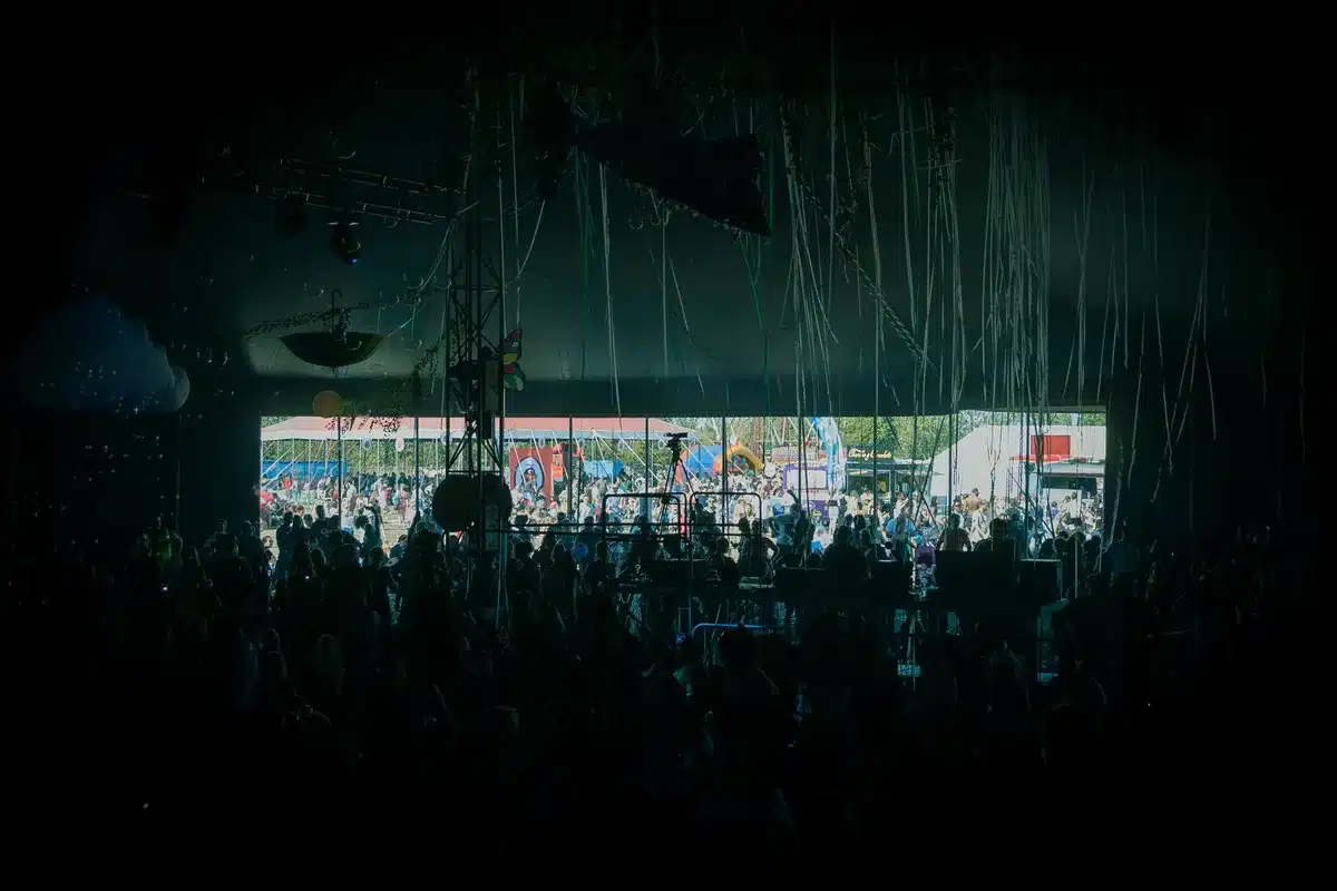 Outdoor summer festival stage with crowds dancing and enjoying live music