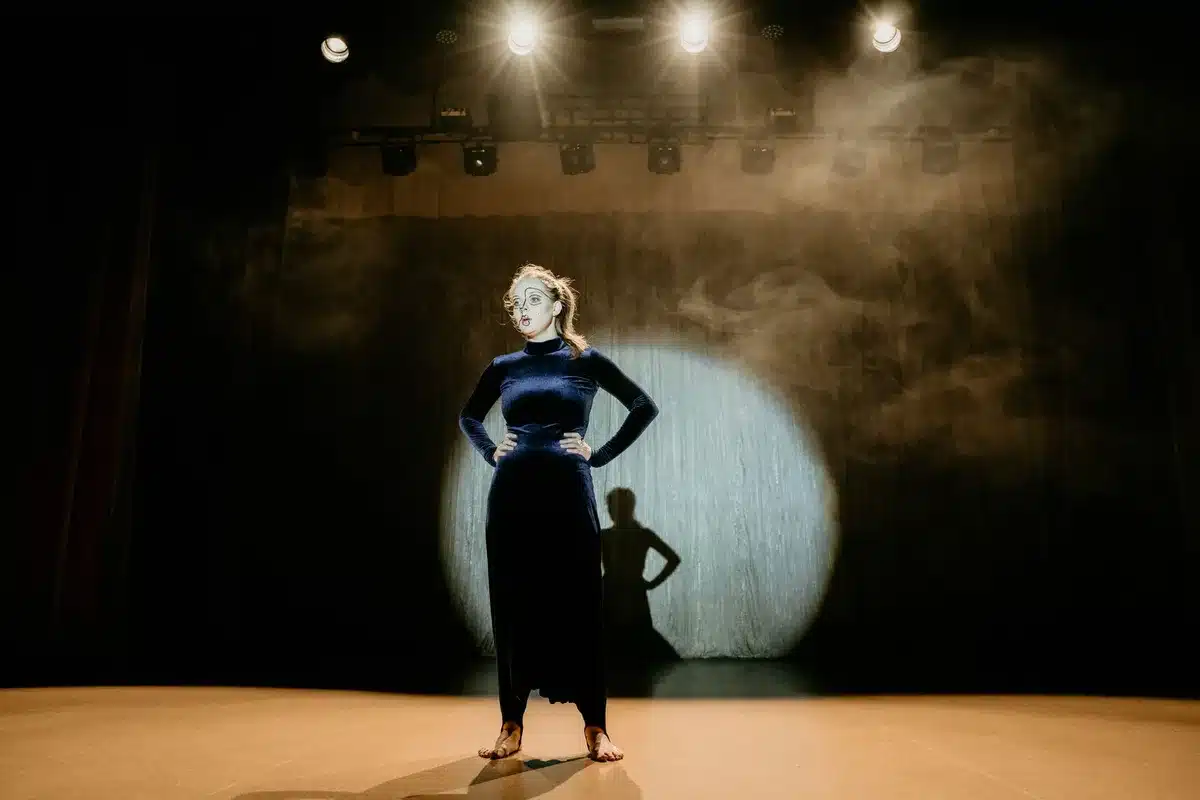 Actress performing exaggerated physical comedy on stage, showcasing fearless comedic commitment