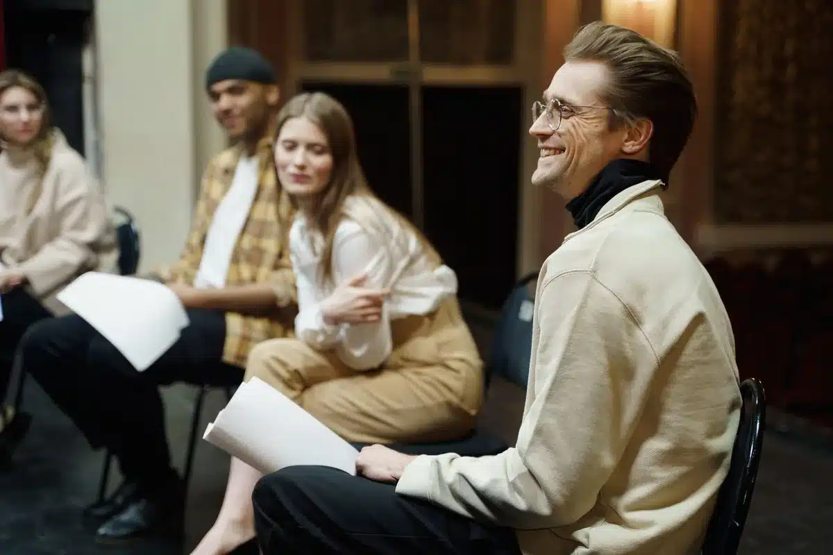 Young adults sharing a lighthearted moment in a living room, embodying ensemble chemistry and character-driven comedy