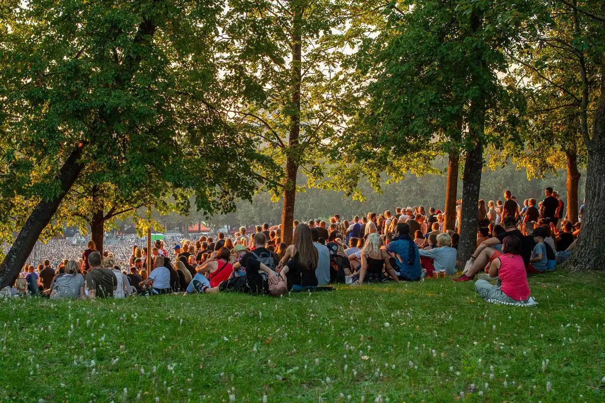 Crowd seated on blankets and standing at an outdoor public park concert