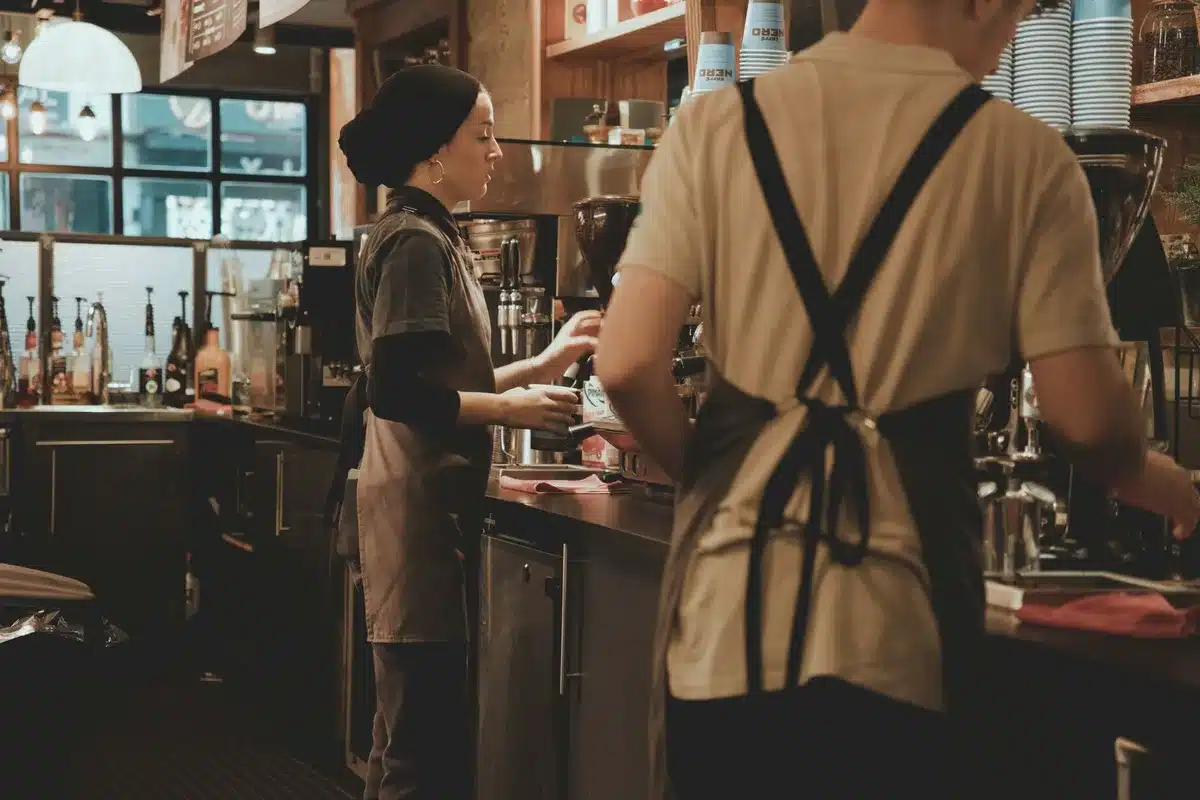 Tired barista working behind a coffee counter, representing the stable job the guitarist almost chose.