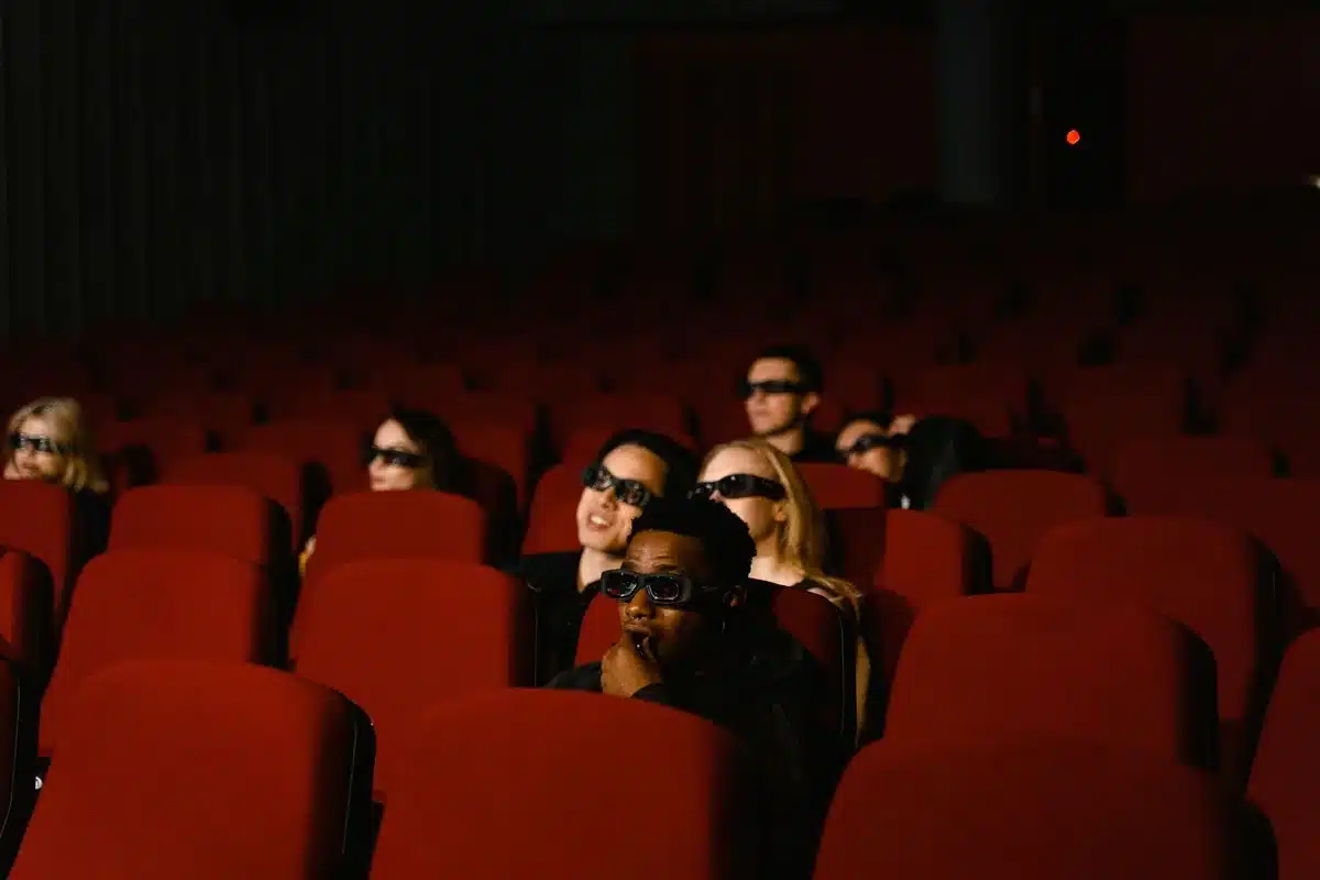 Grupo de jóvenes viendo una película en un cine, compartiendo la experiencia en persona.
