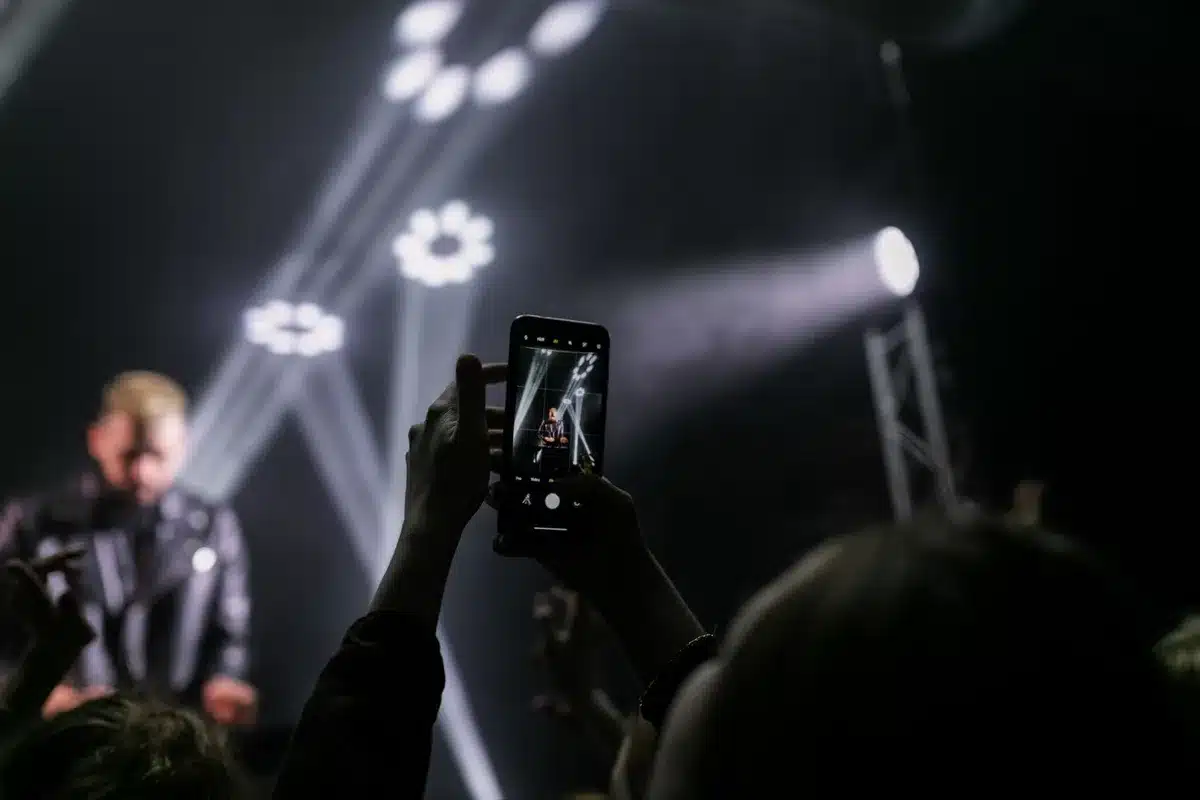 Concert crowd with phones raised, capturing an emotional performance moment