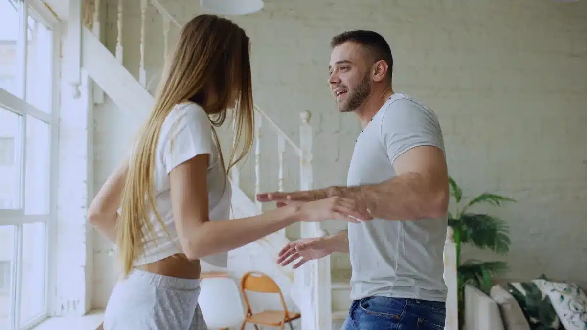 Zwei Menschen tanzen zusammen in einem Wohnzimmer, ein Moment gemeinsamer Freude und Verbindung.