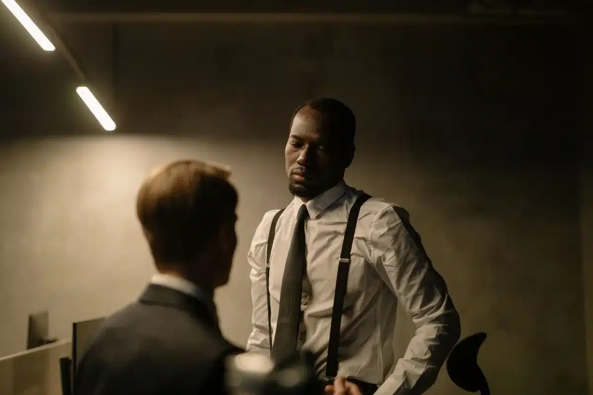 Deux hommes en conversation intense dans un cadre dramatique, illustrant la dynamique tendue entre les personnages