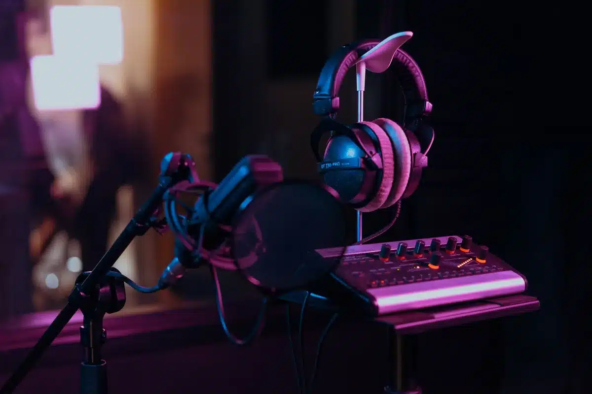 Music producer working at a studio mixing console with headphones, adjusting sound levels