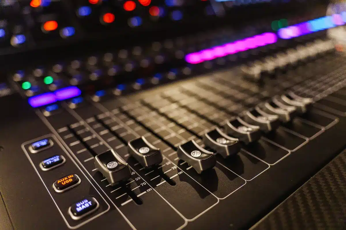 Hand adjusting mixing console knobs in a recording studio