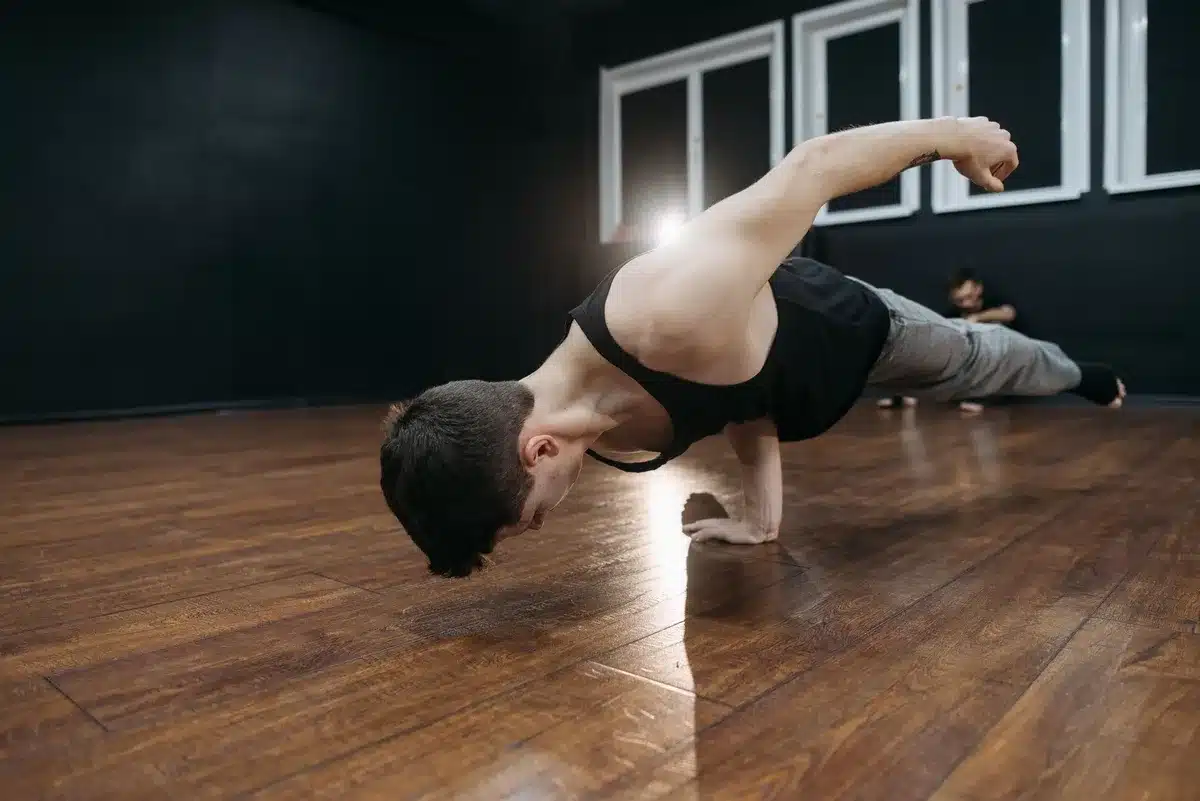 Breakdancer practicing in a cramped studio space with mirrors and minimal lighting