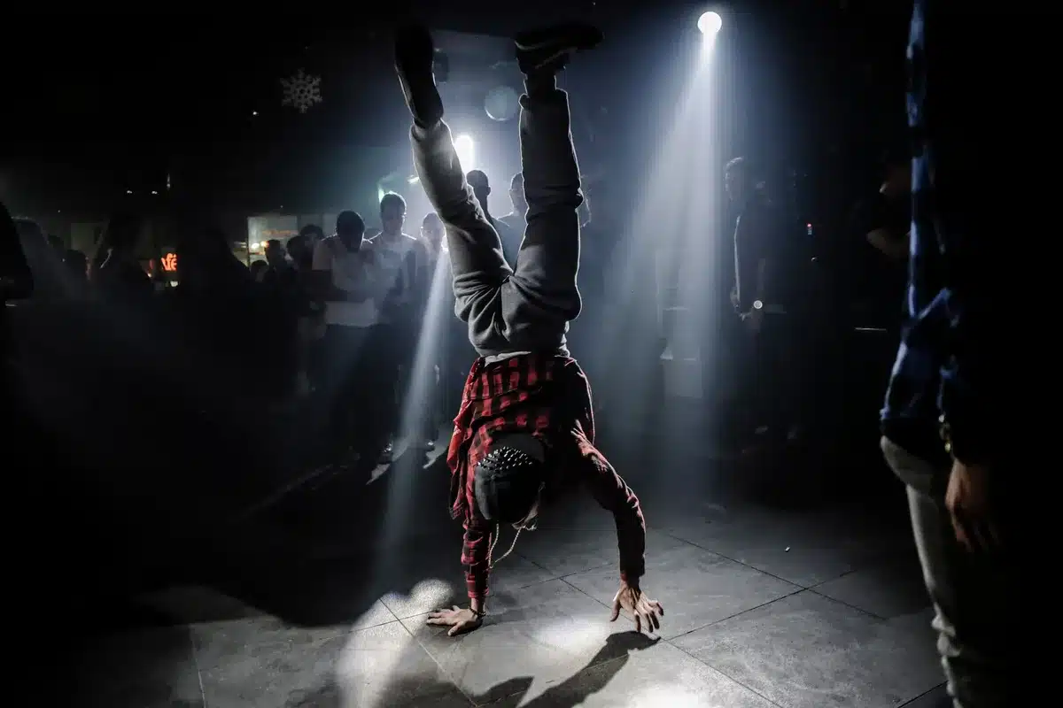 Breakdancer performing dynamic moves in front of an energetic crowd under stage lighting