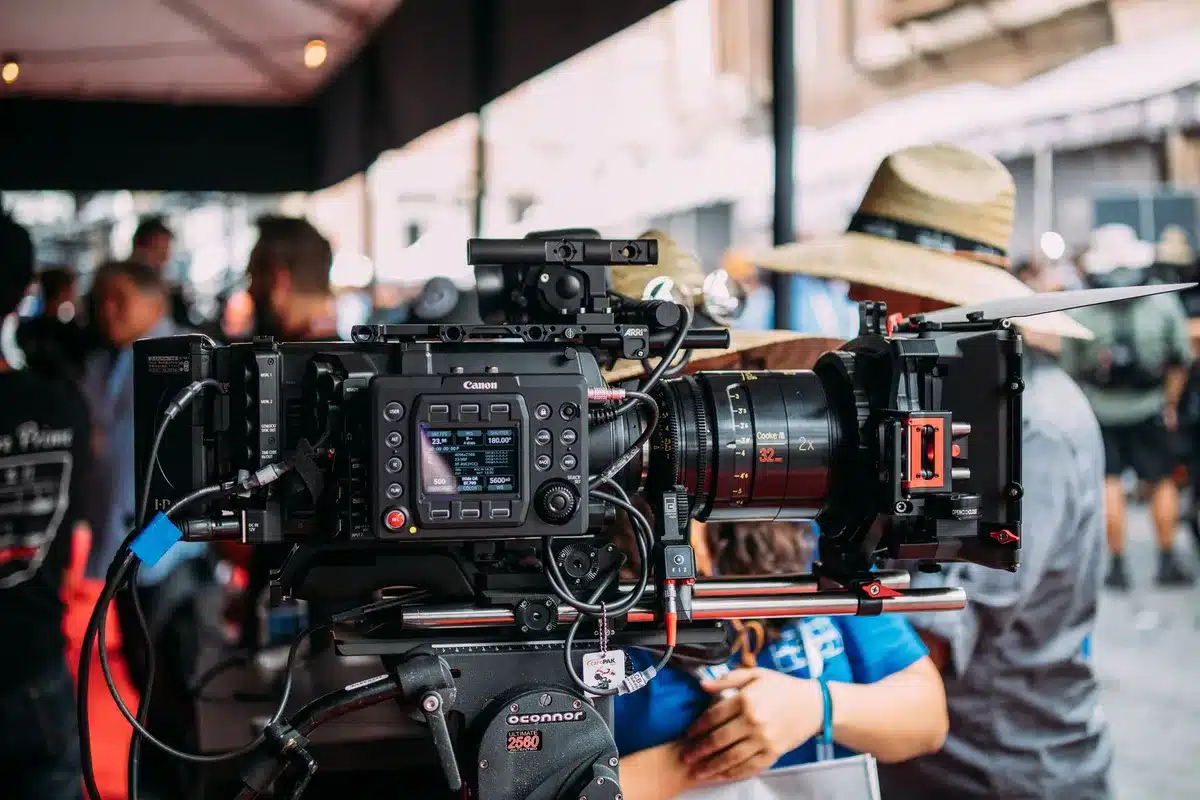 A small documentary film crew with minimal equipment positioned discreetly during a shoot