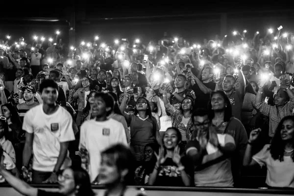 Diverse crowd singing along at a live concert with phones raised