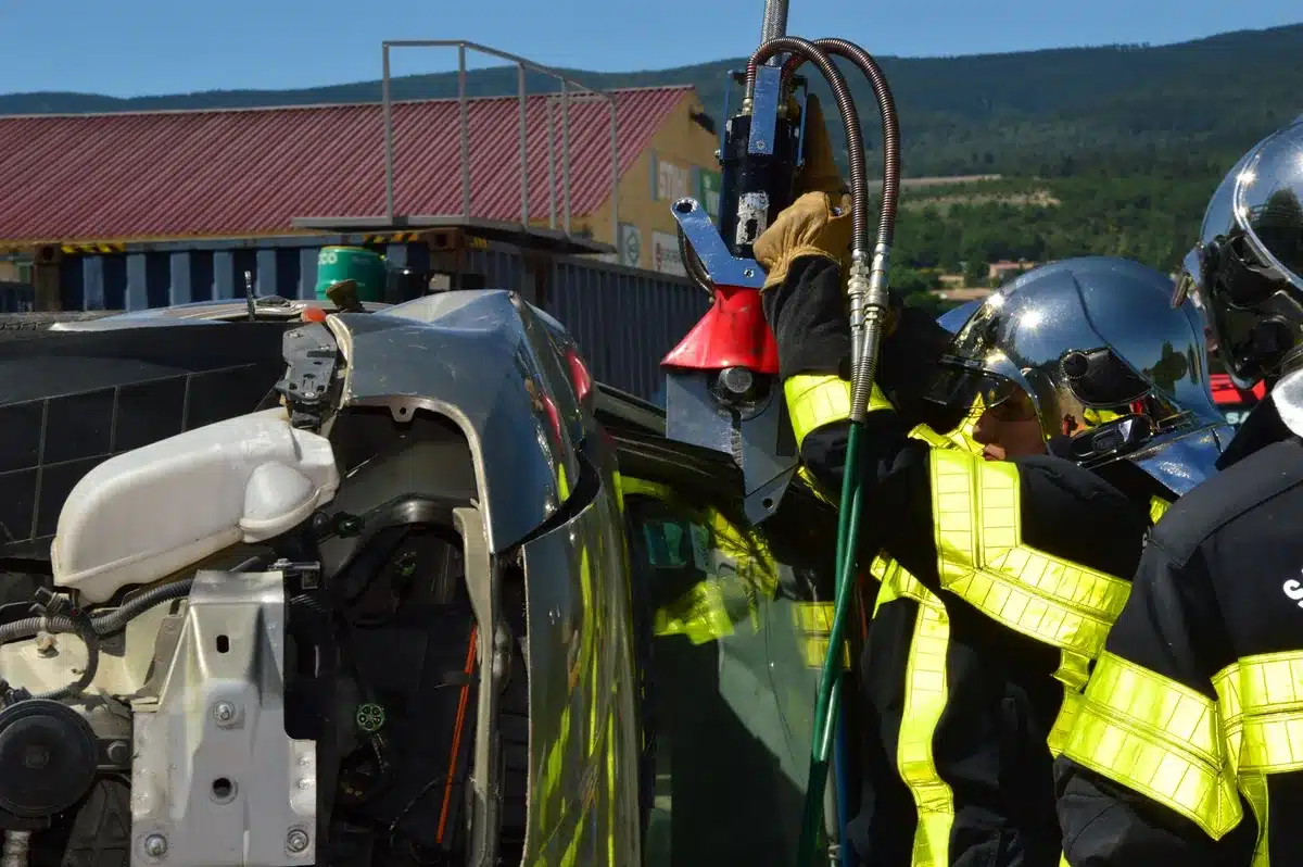 Firefighters using hydraulic tools to extract occupants from a damaged vehicle during emergency response.