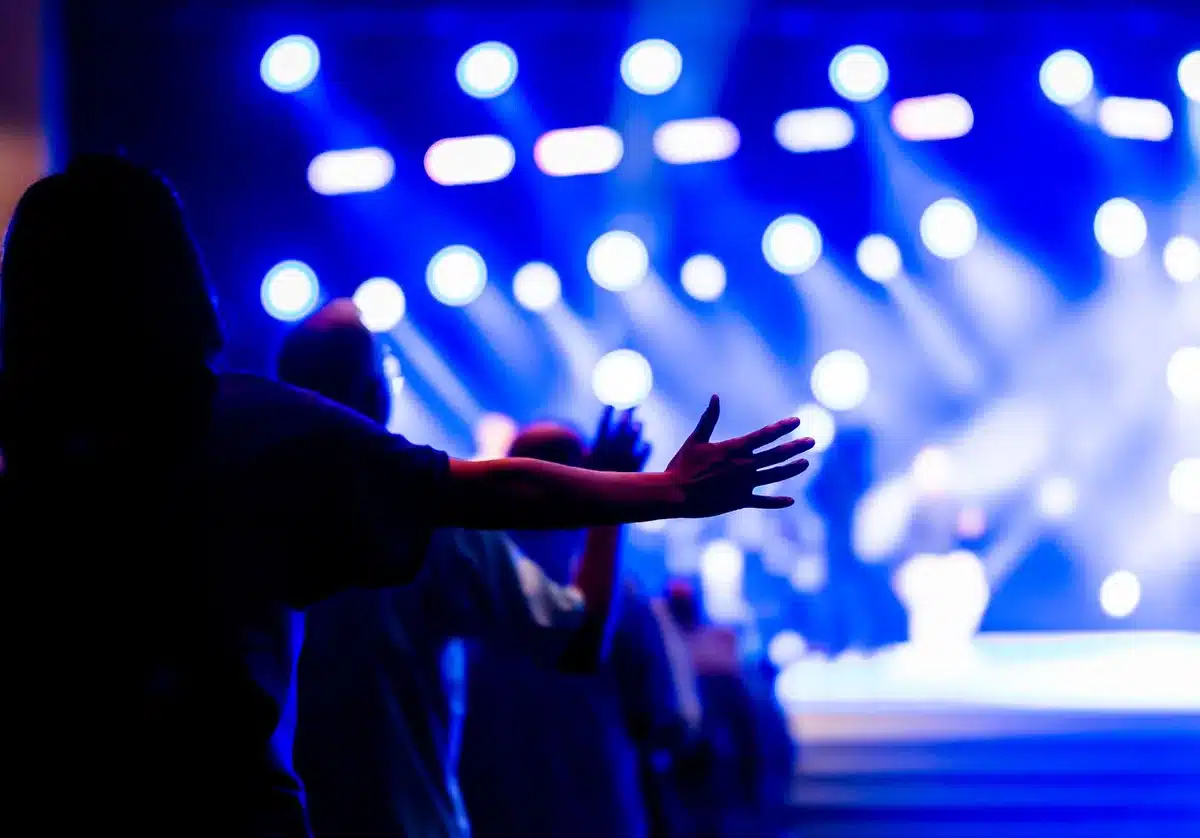 Silhouetted crowd with hands raised during an intense concert performance under stage lighting