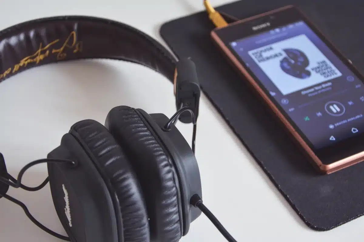 Close-up of headphones resting on a device displaying a music streaming app