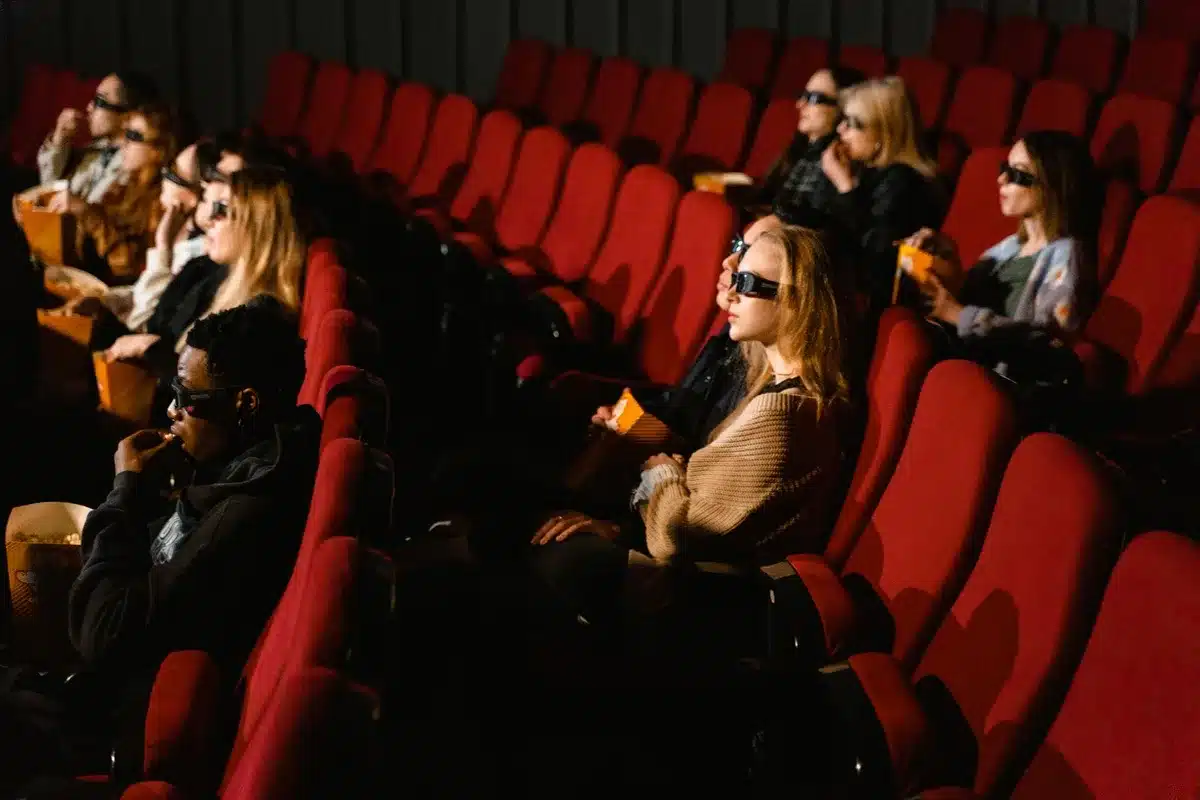 Audiences in a dark movie theater watching a blockbuster film on the big screen