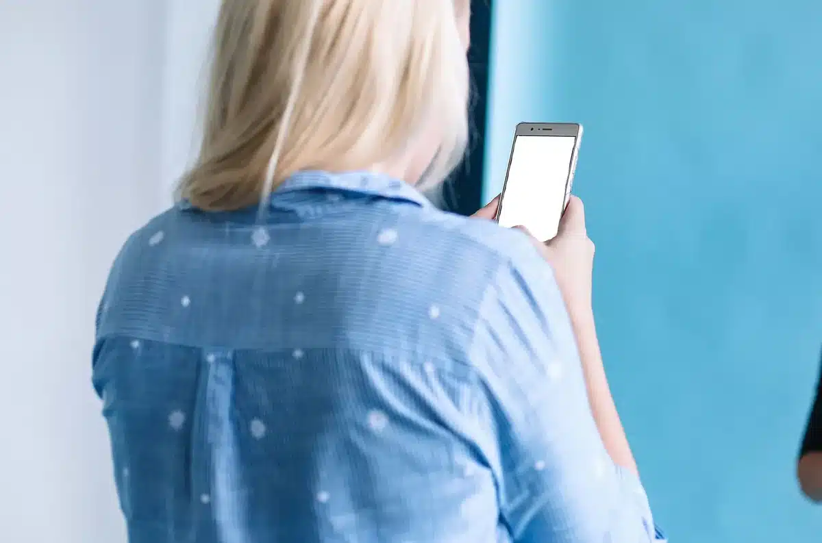 Mujer sosteniendo un teléfono inteligente mientras interactúa en redes sociales