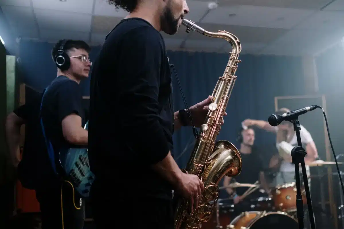 Músicos grabando en estudio con instrumentos diversos durante una sesión de composición colaborativa.
