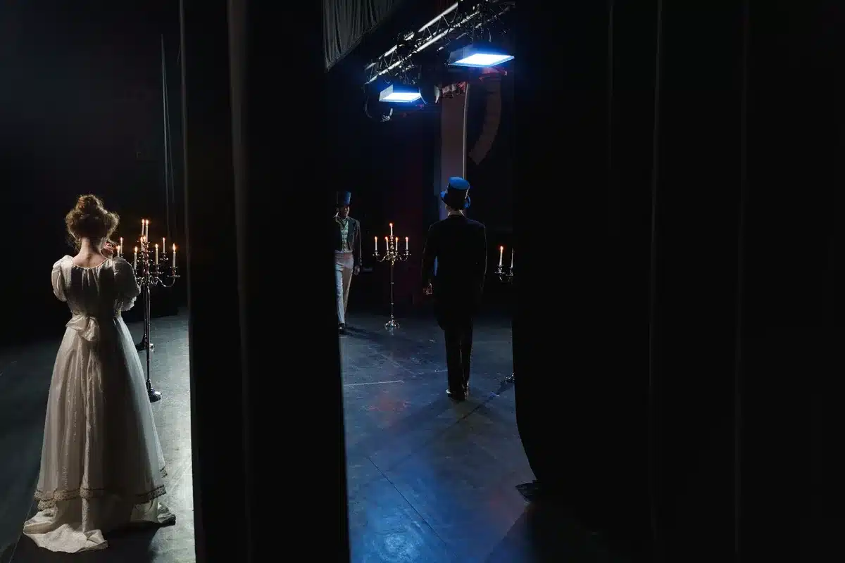 Performer on stage under dramatic theatrical lighting in costume and makeup