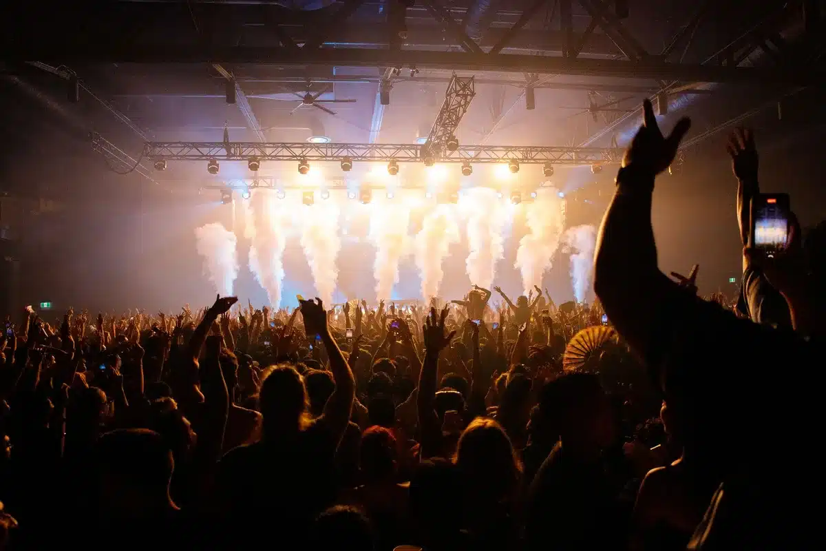 Boisterous live audience with raised hands and energetic crowd during a televised event
