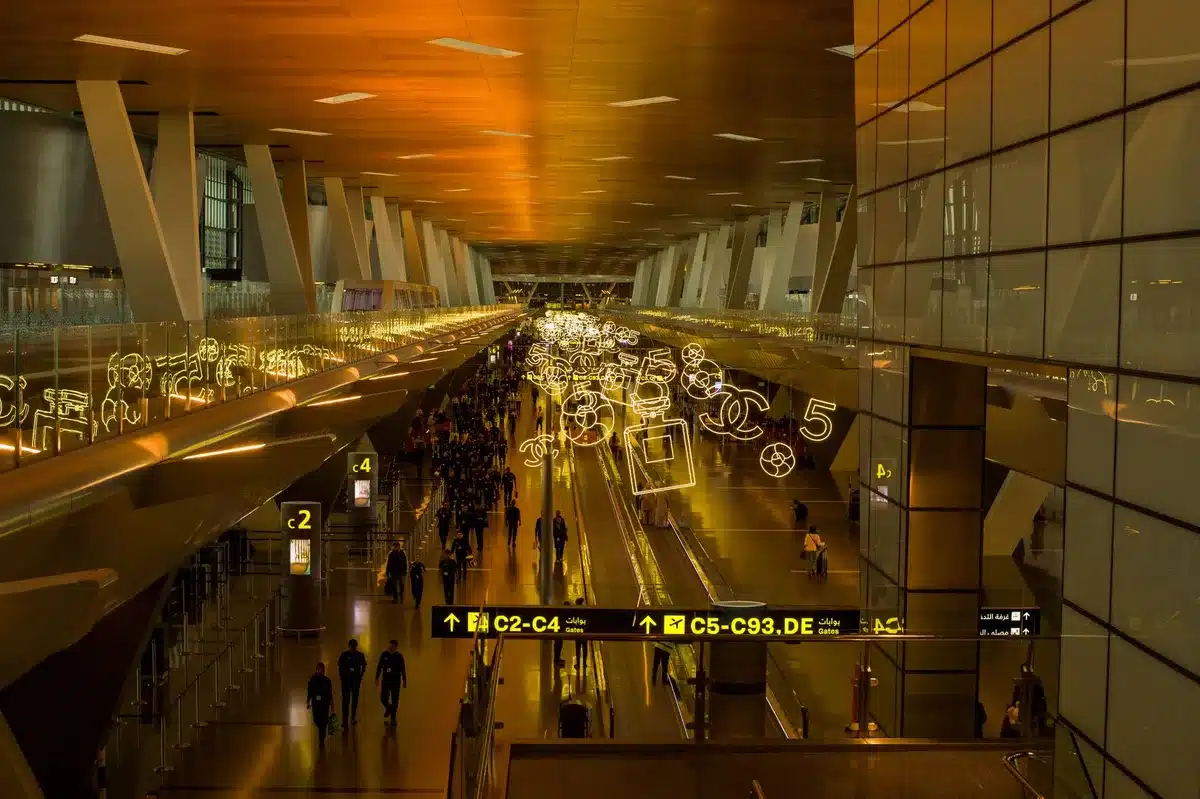 Modern airport terminal with directional signs, departure boards, and infrastructure elements