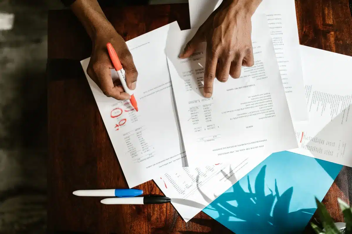 Fact-checker reviewing court documents and records at a desk with multiple papers and a computer.