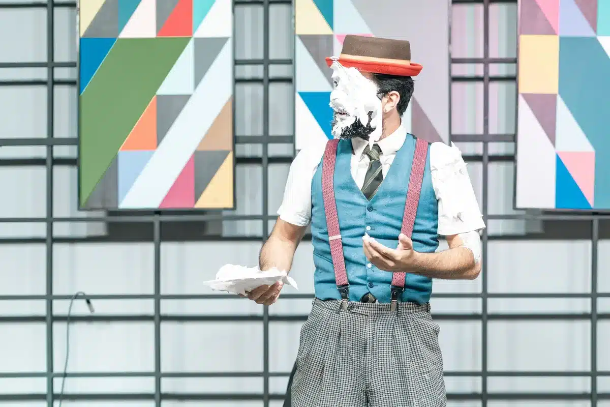 Performer executing physical comedy on stage with exaggerated movement