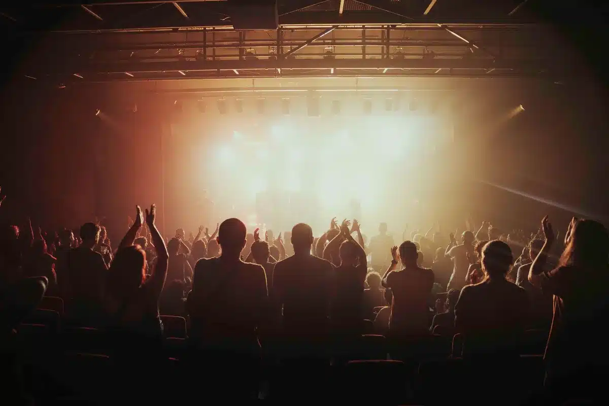 Anonymous crowd outside a theater at dusk, silhouettes against marquee light