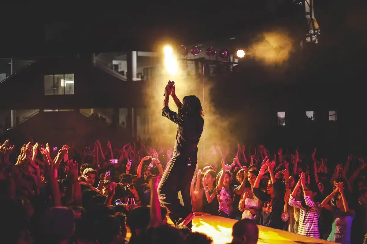 Silhouetted performer mid-song with smartphone recording the moment