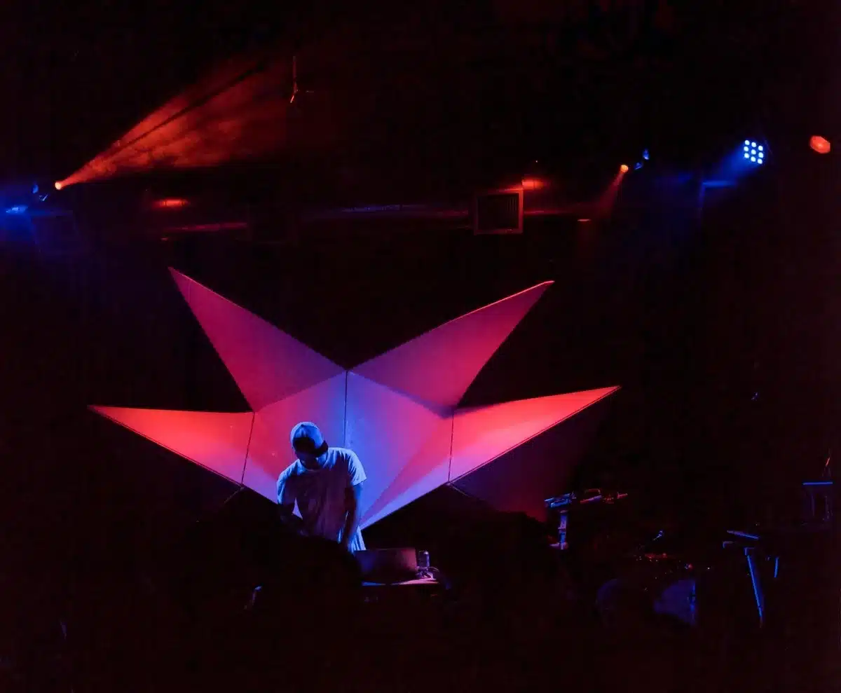Crowded mid-sized club with fans near stage and hands raised