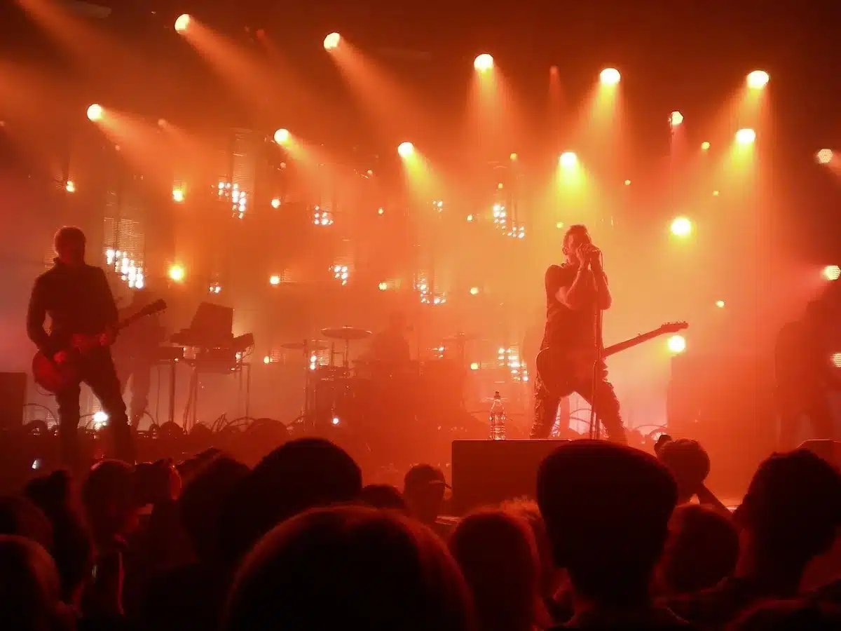 Guitarist mid-solo under stage lights with drum kit behind