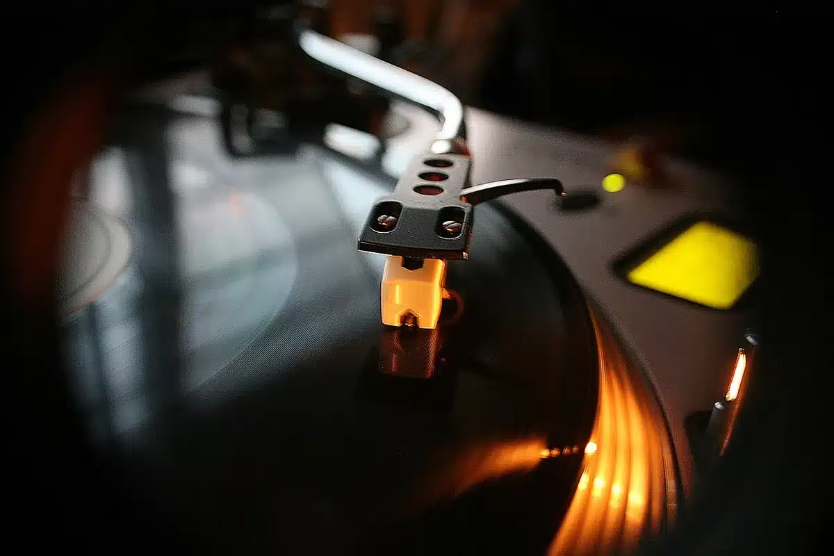 Silhouetted hands flipping vinyl on a dim studio table with scattered papers