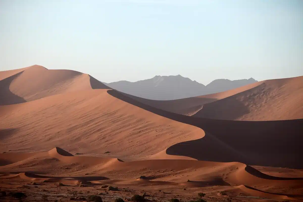 Dust storm reducing visibility across a desert landscape with distant figures