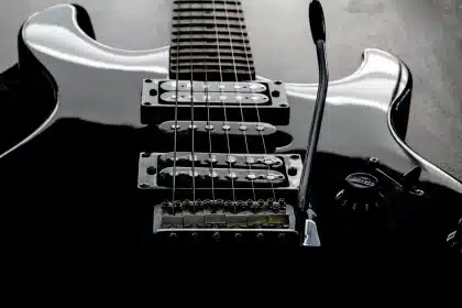 Hands holding an electric guitar and a handwritten setlist on a small stage