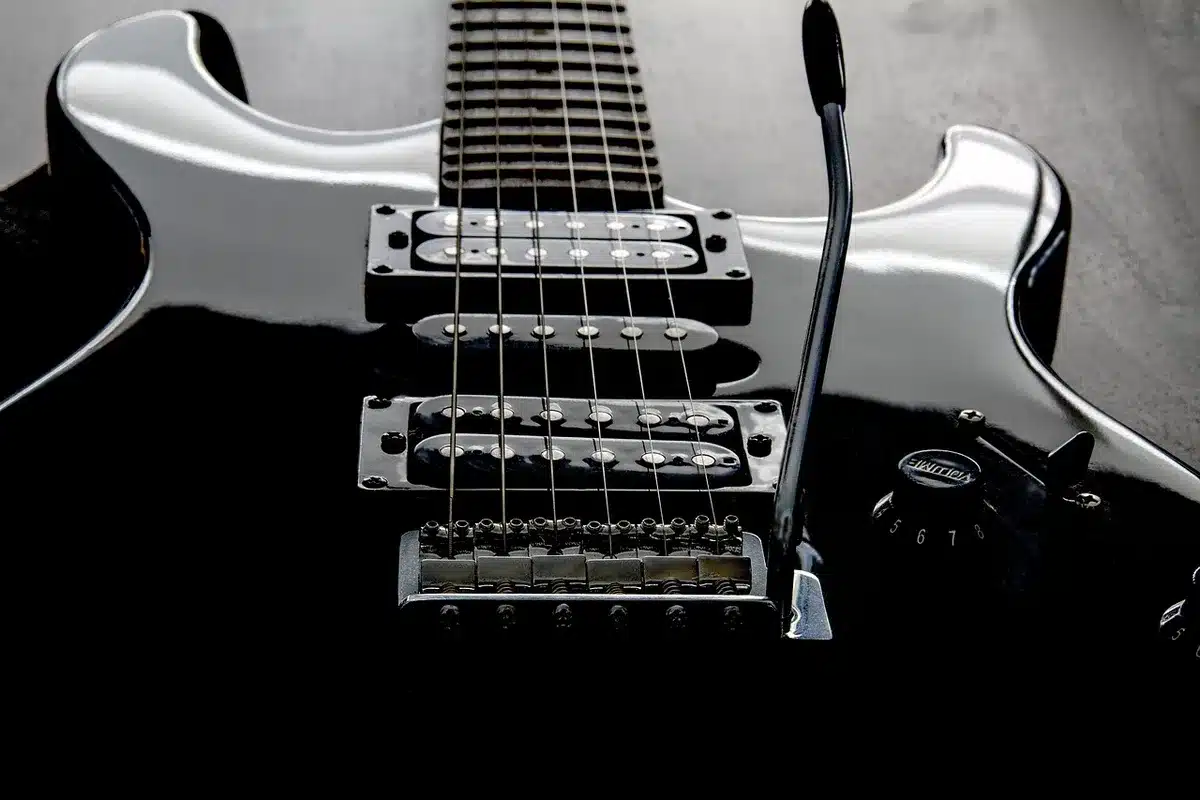 Hands holding an electric guitar and a handwritten setlist on a small stage