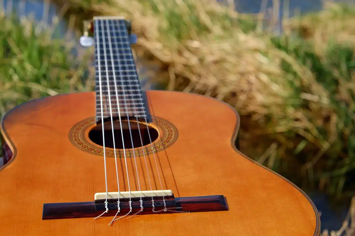 Home studio view with acoustic guitar and laptop showing waveforms, suggesting genre-mixing production