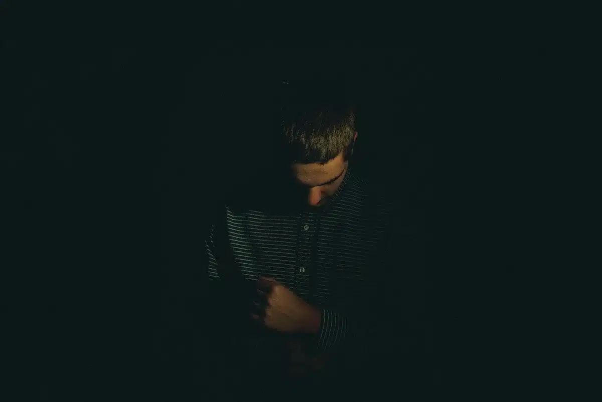 Person with headphones in a dim room, concentrating on music