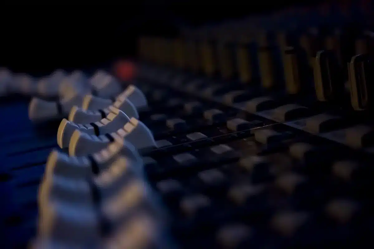 Hands adjusting ambient music equipment in a dim studio