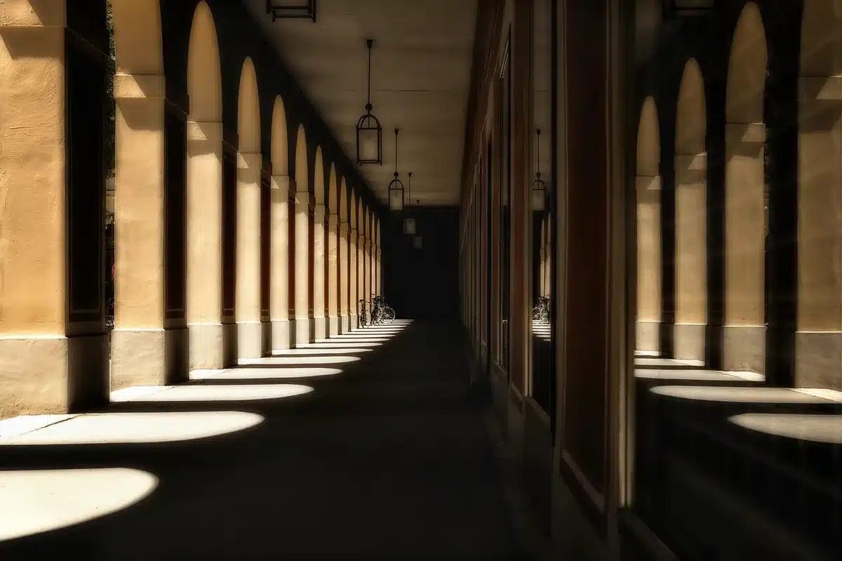 Empty neon-lit hotel corridor with rain reflections and a distant silhouetted figure