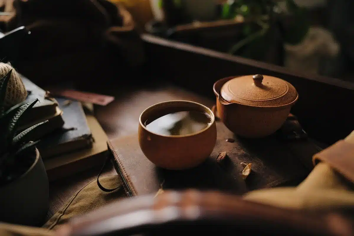 Candle and steaming mug on a table with a soft throw nearby