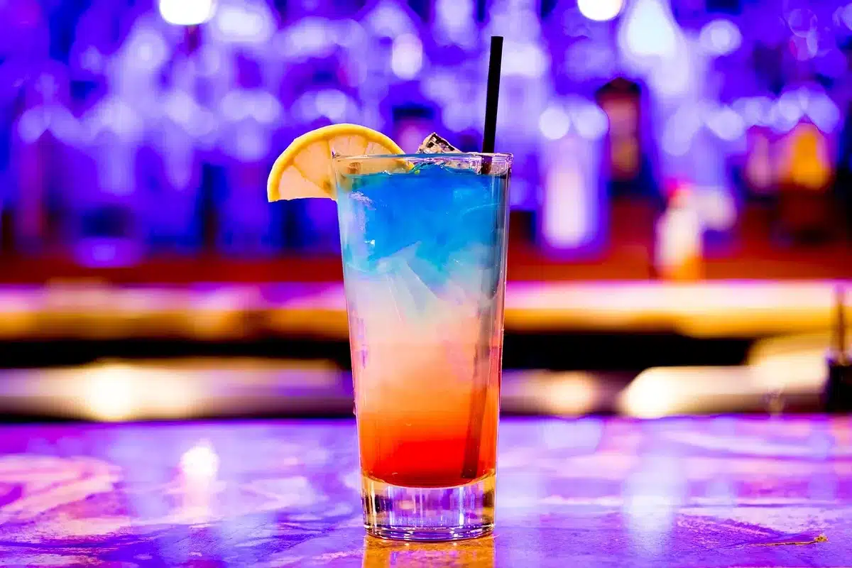 Two people at a bar table, one turned away, bartender blurred in background