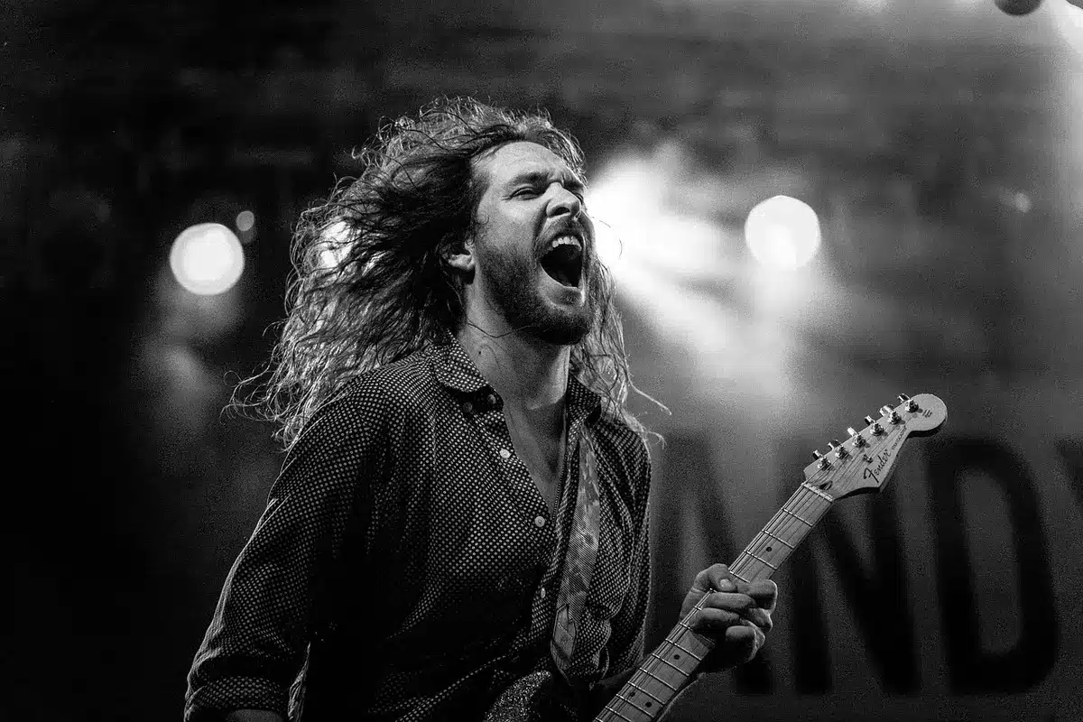 A rock performer on stage under dramatic lighting in a 1970s concert setting