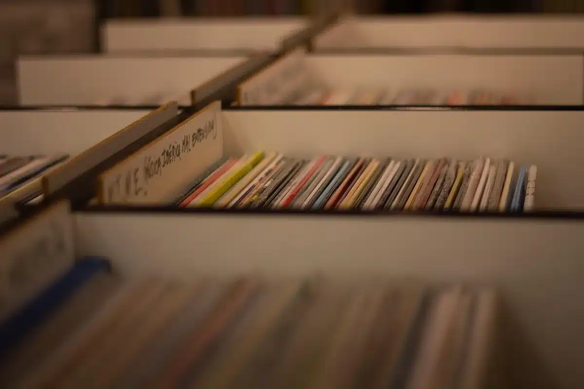 Person selecting a vinyl record from a shelf, hinting at digging deeper into albums