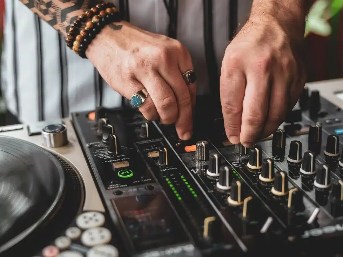 Producer's hands adjusting knobs on a mixing console to shape sound