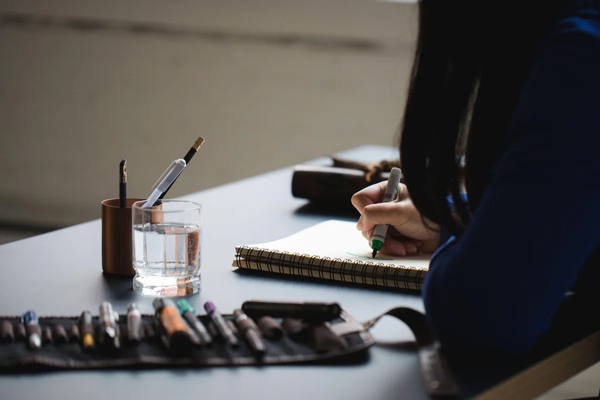 Close-up of hands and a notebook across a dim interrogation table